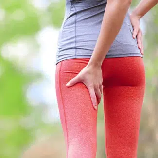 Mujer con ropa deportiva sujetando la parte posterior de su pierna