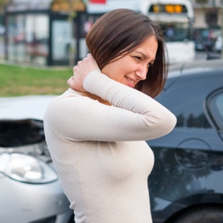 Una mujer se sujeta el cuello con dolor, probablemente por un latigazo cervical provocado por un accidente de tráfico