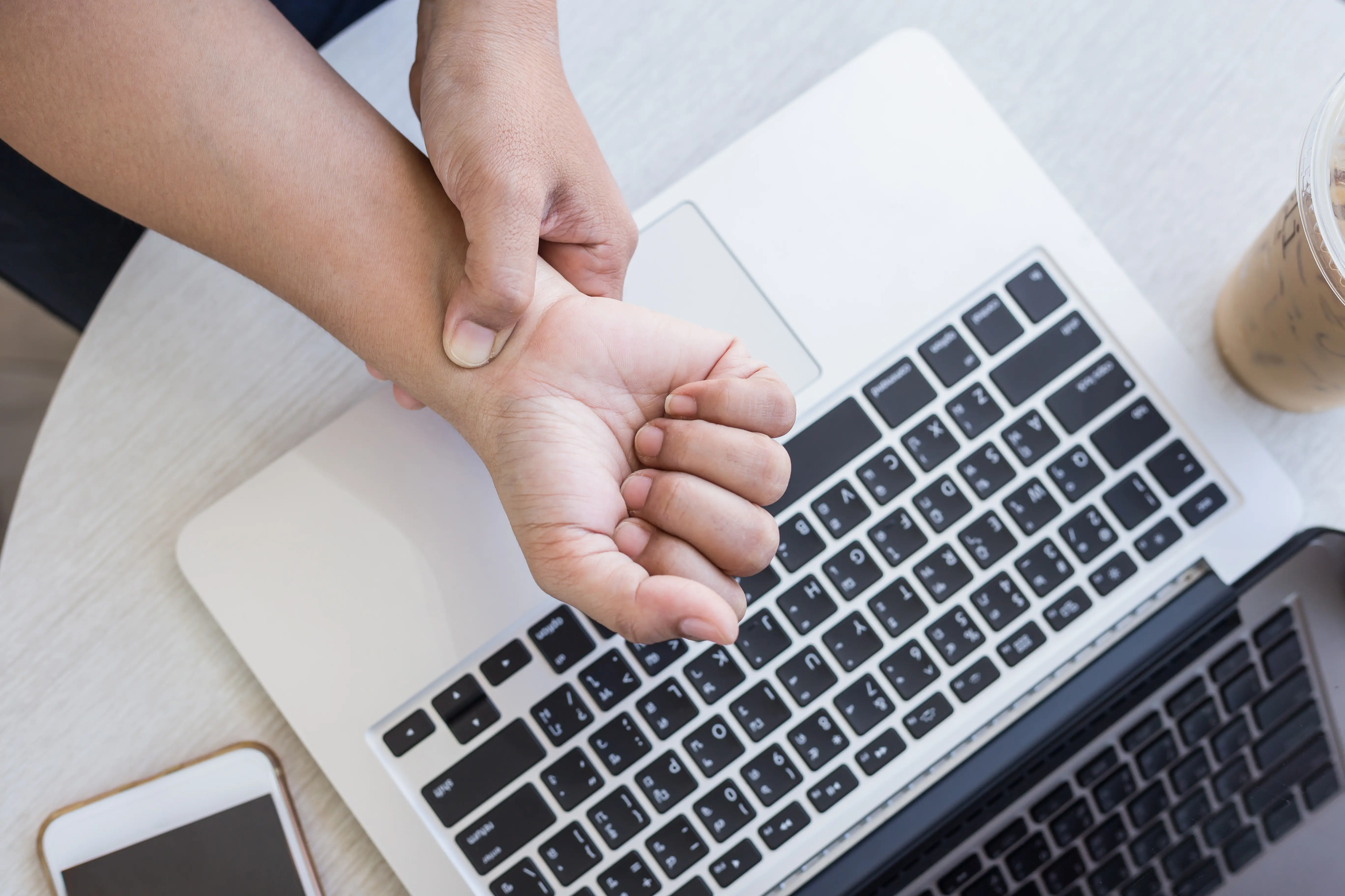 Person rubbing wrist in pain while working on computer