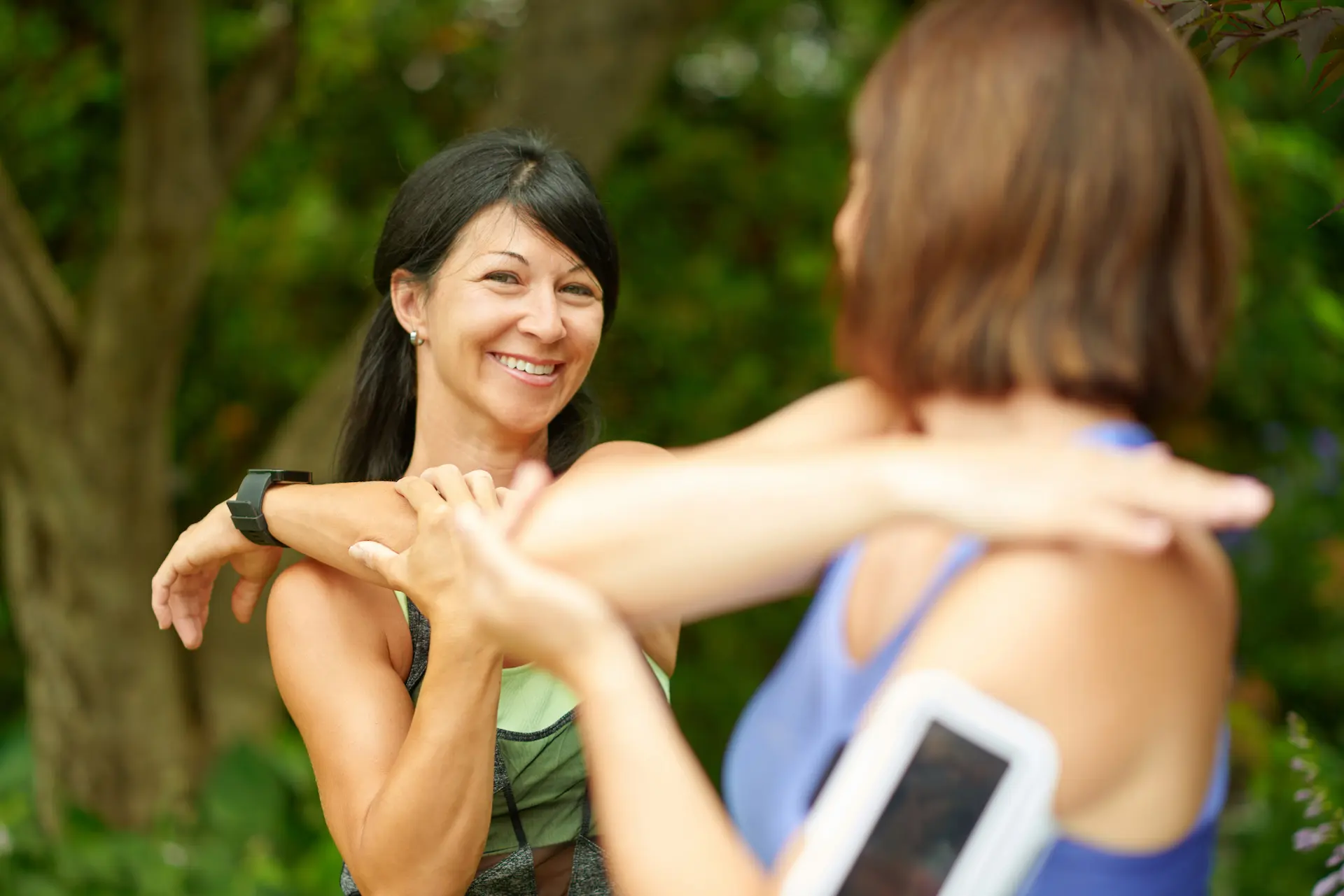 Two women stretching their shoulders before exercise