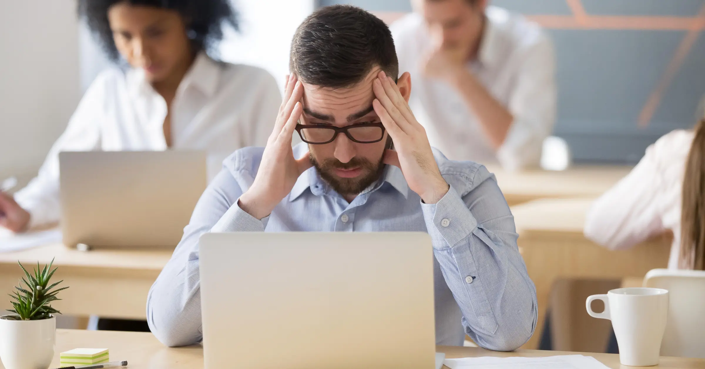 a stressed and tired man looks at his laptop