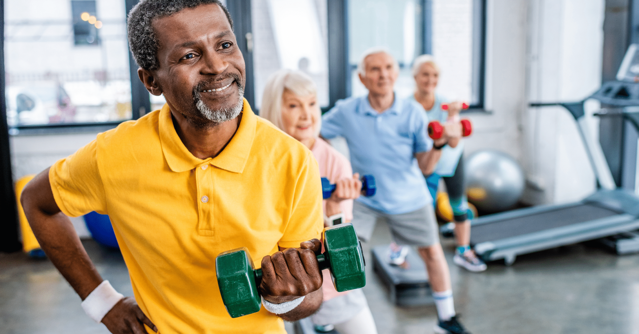a elderly man lifts free weights at the gym