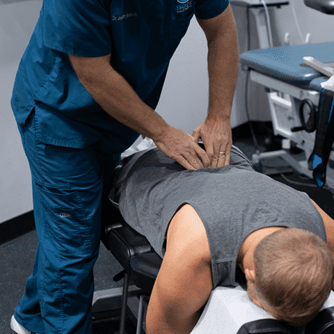 Man receiving manual adjustment on his mid to low back
