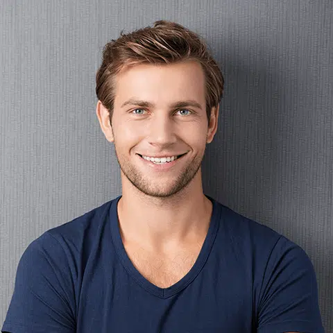 young man in navy blue leaning on gray wall