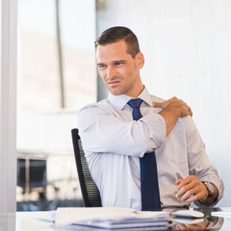 Young businessman at work suffering from shoulder pain.