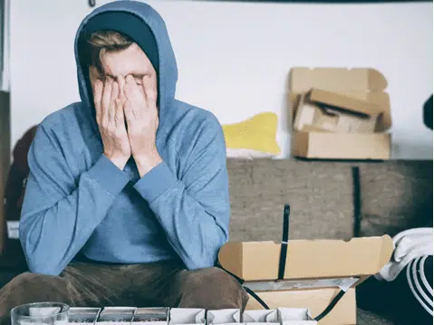 Stressed male sitting on couch with hands on face