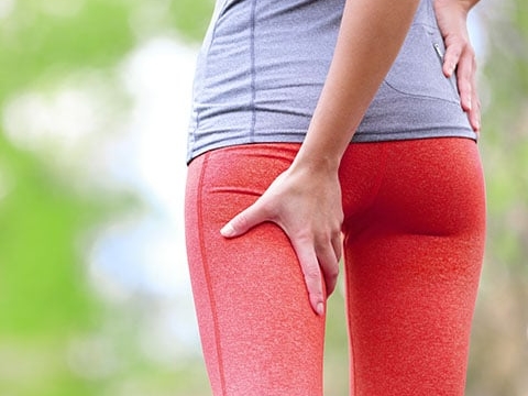 Mujer con ropa deportiva sujetando la parte posterior de su pierna