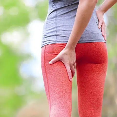 woman-holding-hamstring-in-pain Woman in athletic wear holding back of her leg