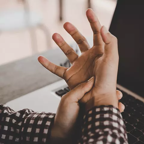 Mujer con la mano en el dolor sobre un ordenador portátil