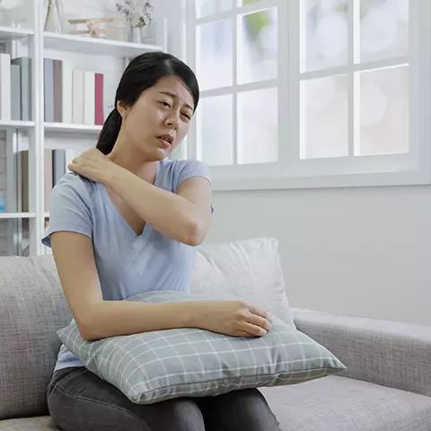 woman rubbing shoulder in pain